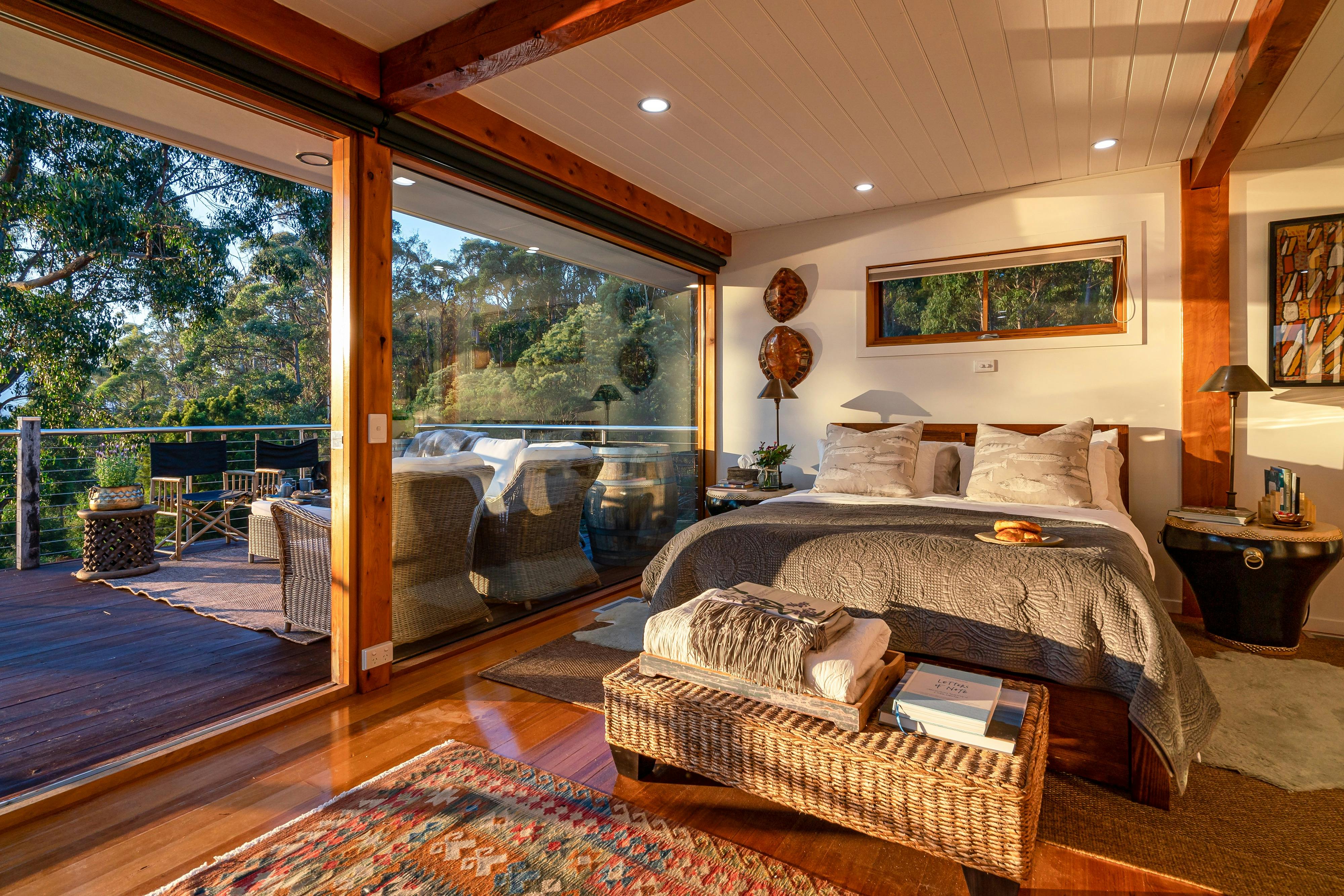 An interior photo of the Huon River Hideaway bedroom setting facing outwards through large windows