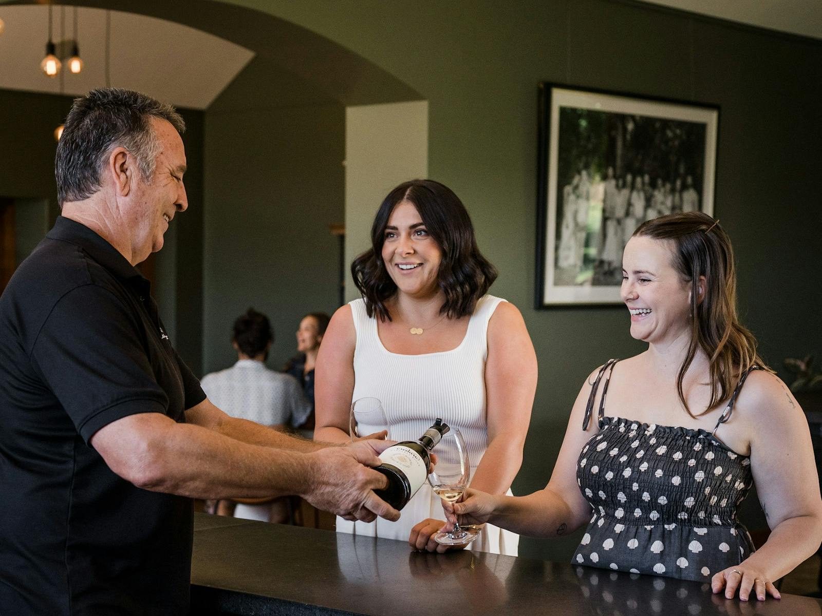 Credaro employee pouring wine tasting for two female light-skinned women
