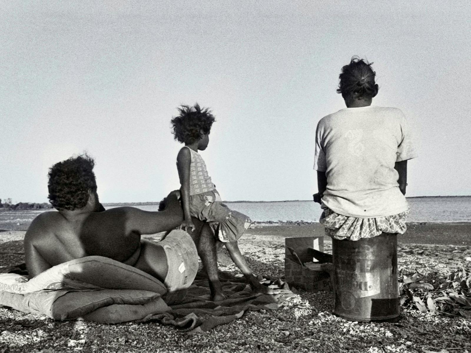 A sepia photograph of a family on a beach.