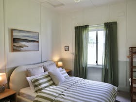 Queen bed positioned near a window with bedside tables on either side.