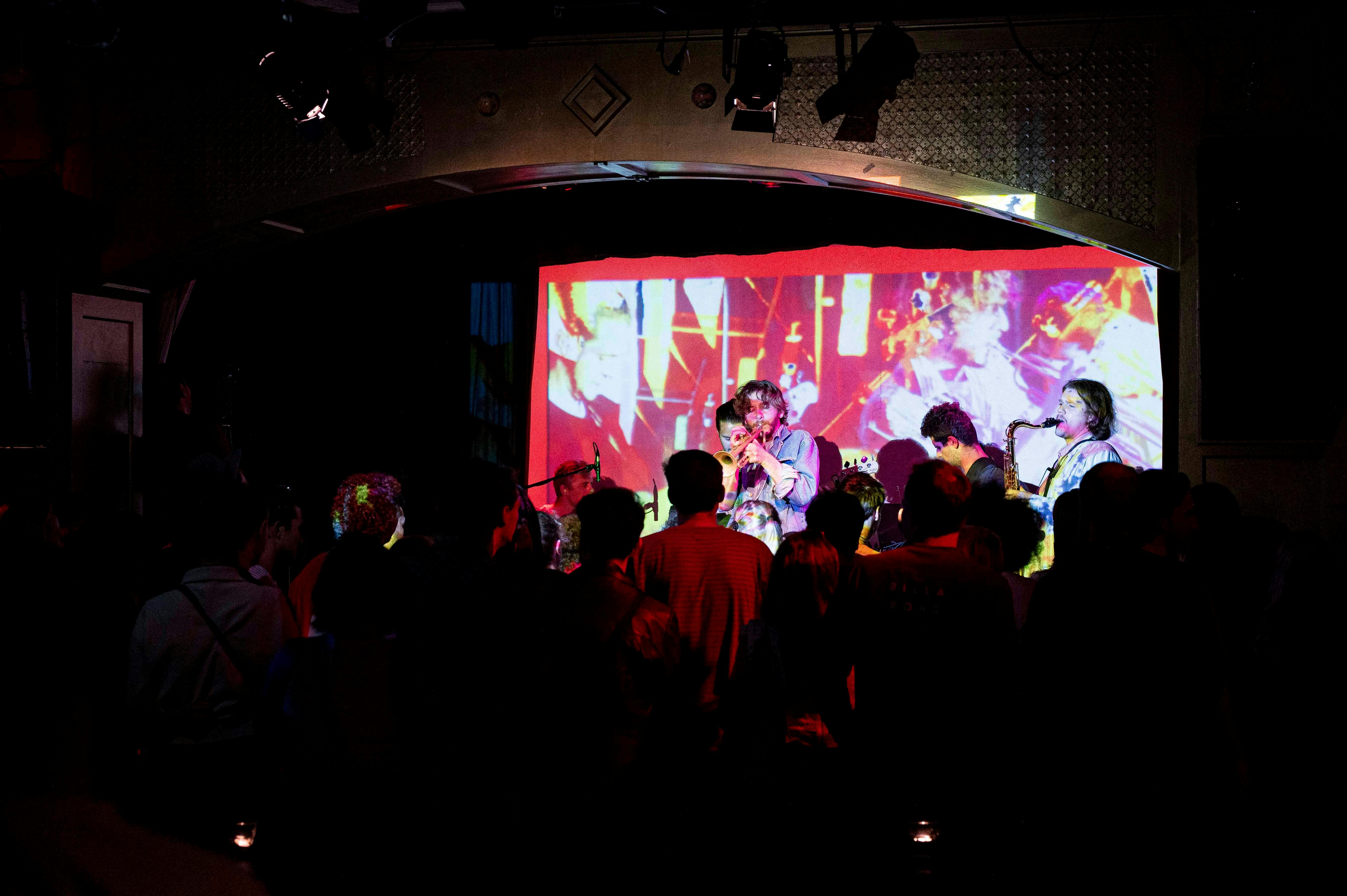 Live band perform onstage with colourful live projections on the walls.