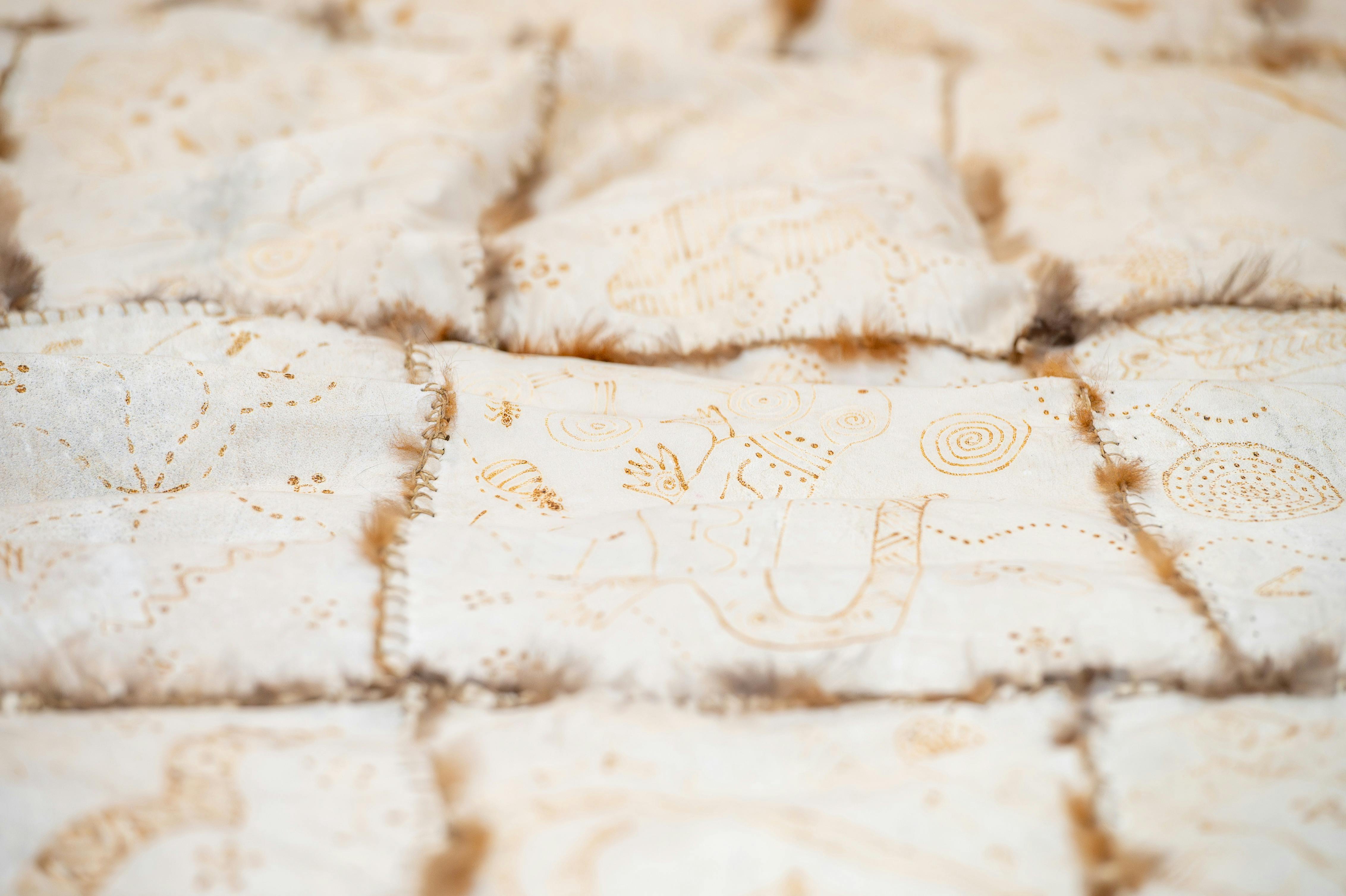 A close up of a possum skin cloak featuring First Nations artists' artworks