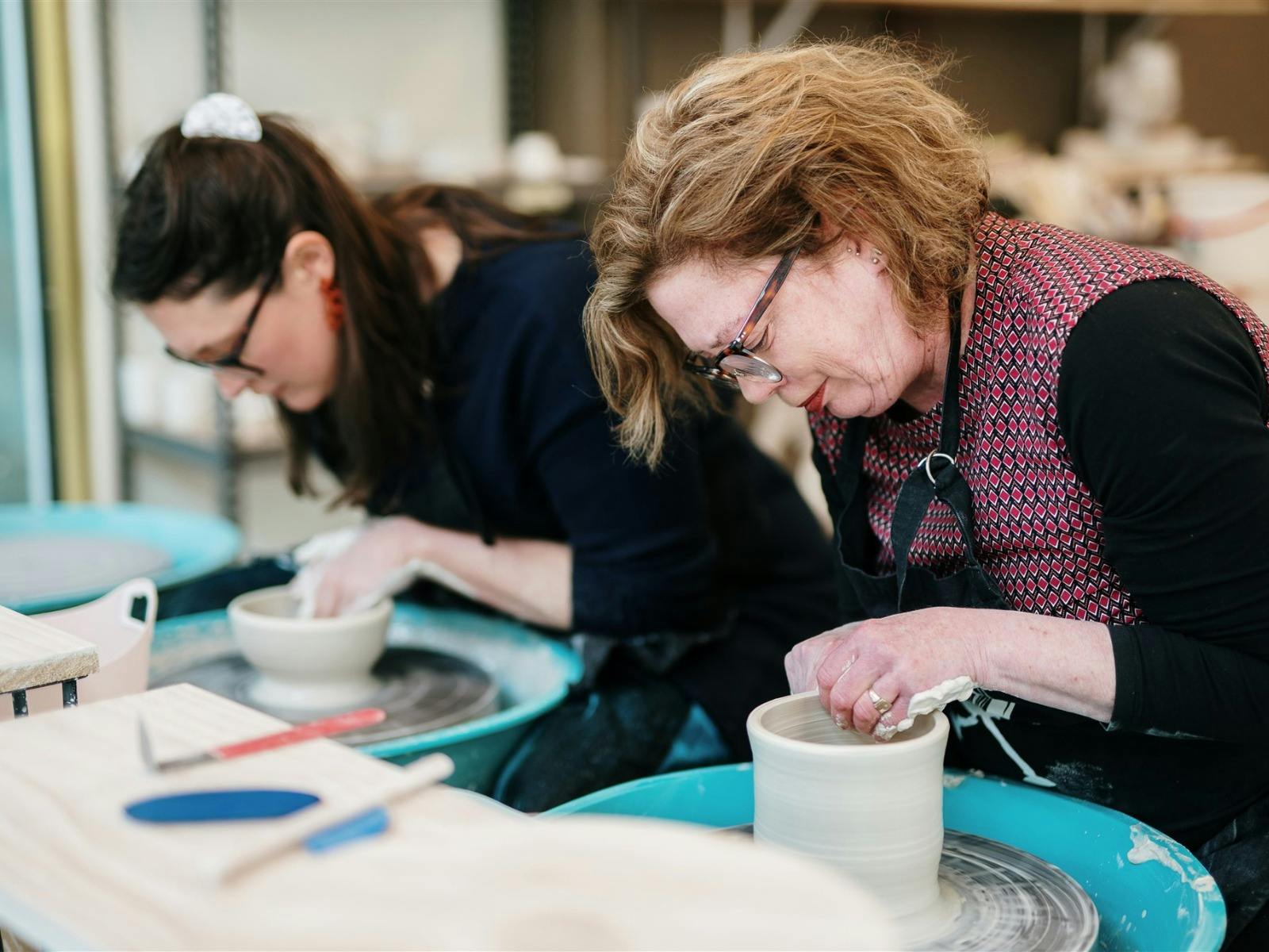 Two women doing wheel pottery