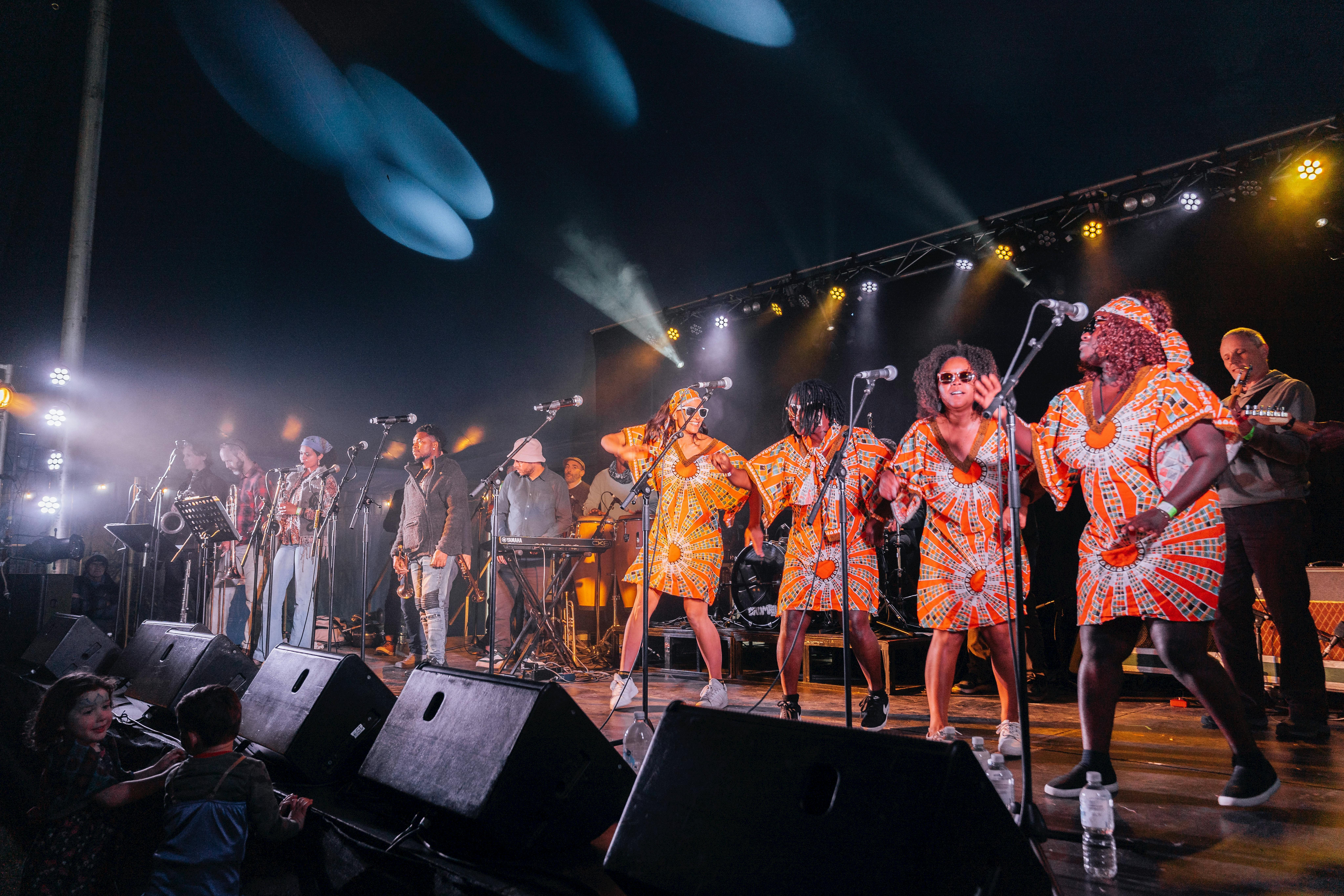 Dancers and musicians from Public Opinion Afro Orchestra on stage in the big tent