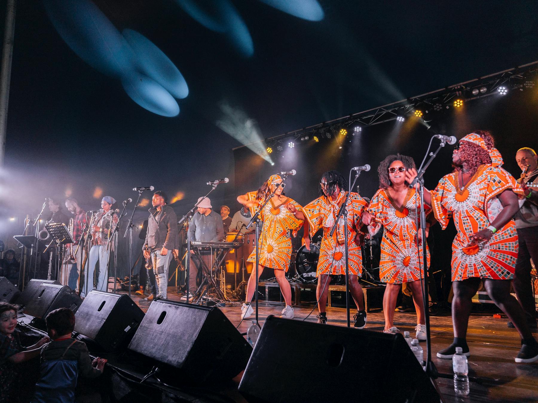 Dancers and musicians from Public Opinion Afro Orchestra on stage in the big tent