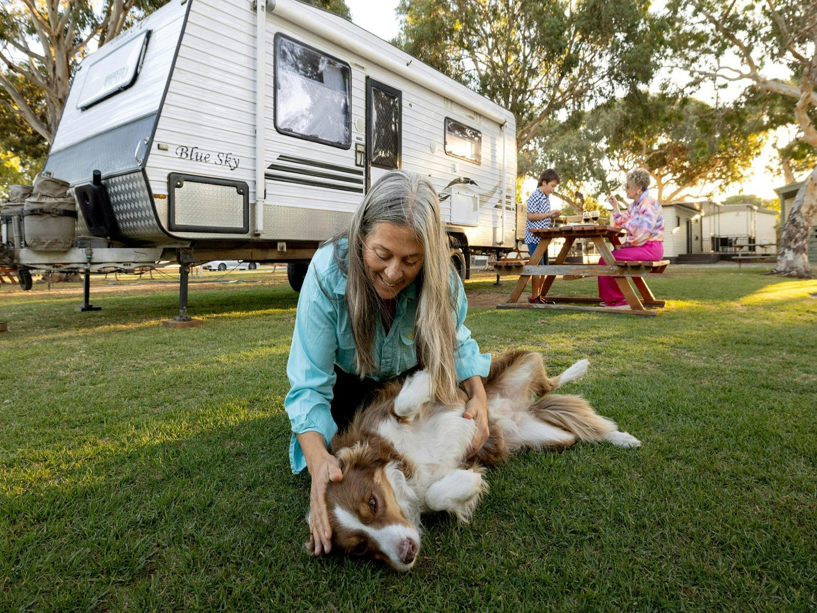 A guest having fun with their dog at a powered site on Beachside Holiday Park