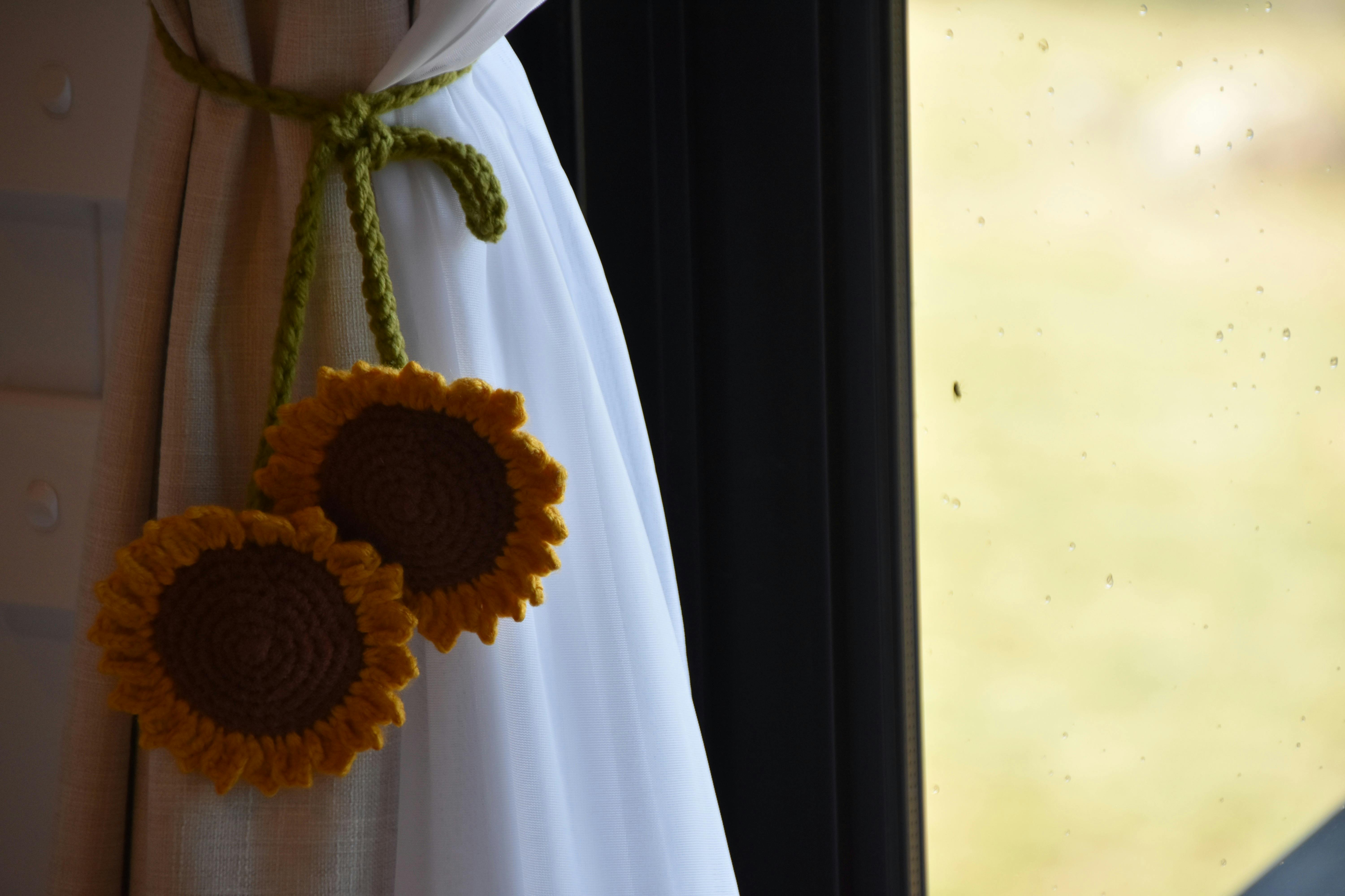 Close-up of sunflower decoration tied to curtain.