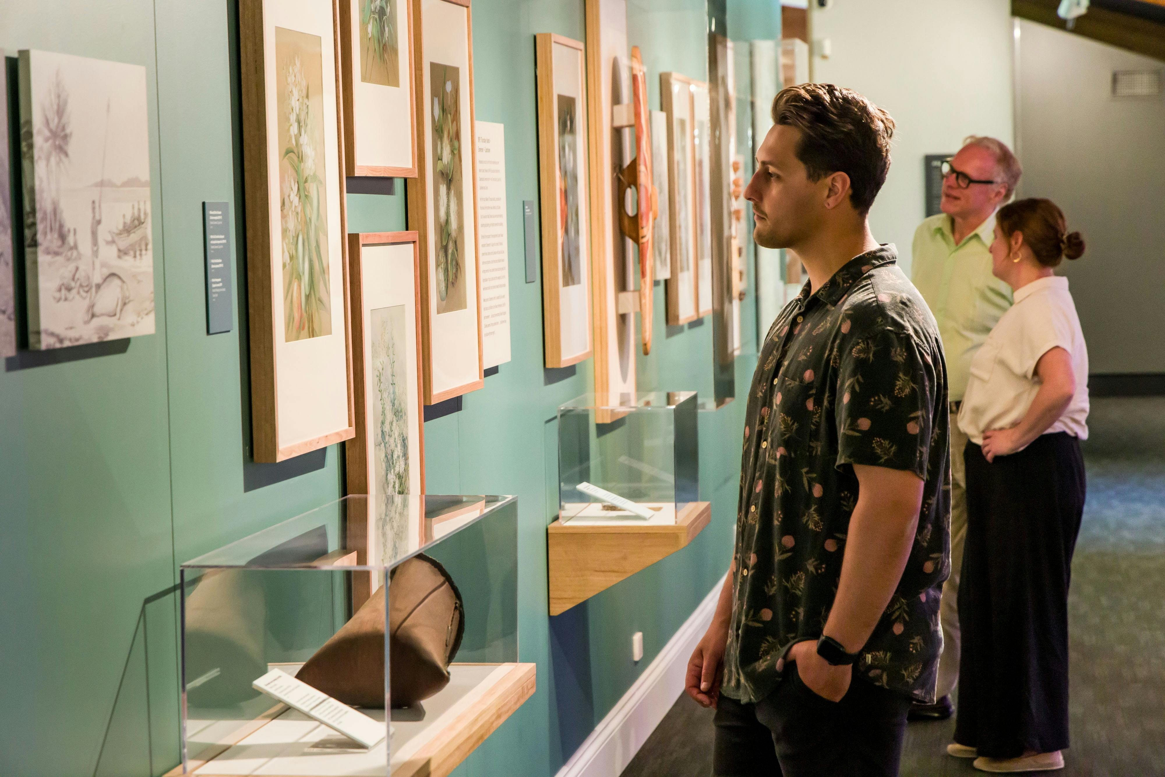 Visitors looking at watercolour artworks hung on wall