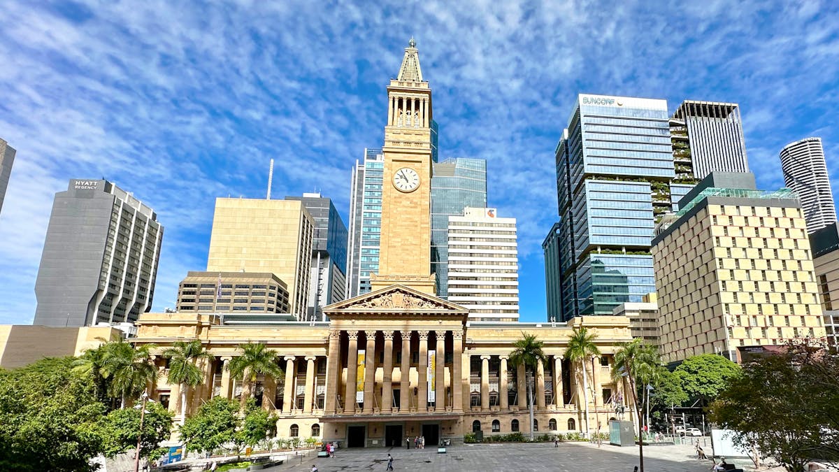 Brisbane City Hall with clock tower in the middle and blue sky behind