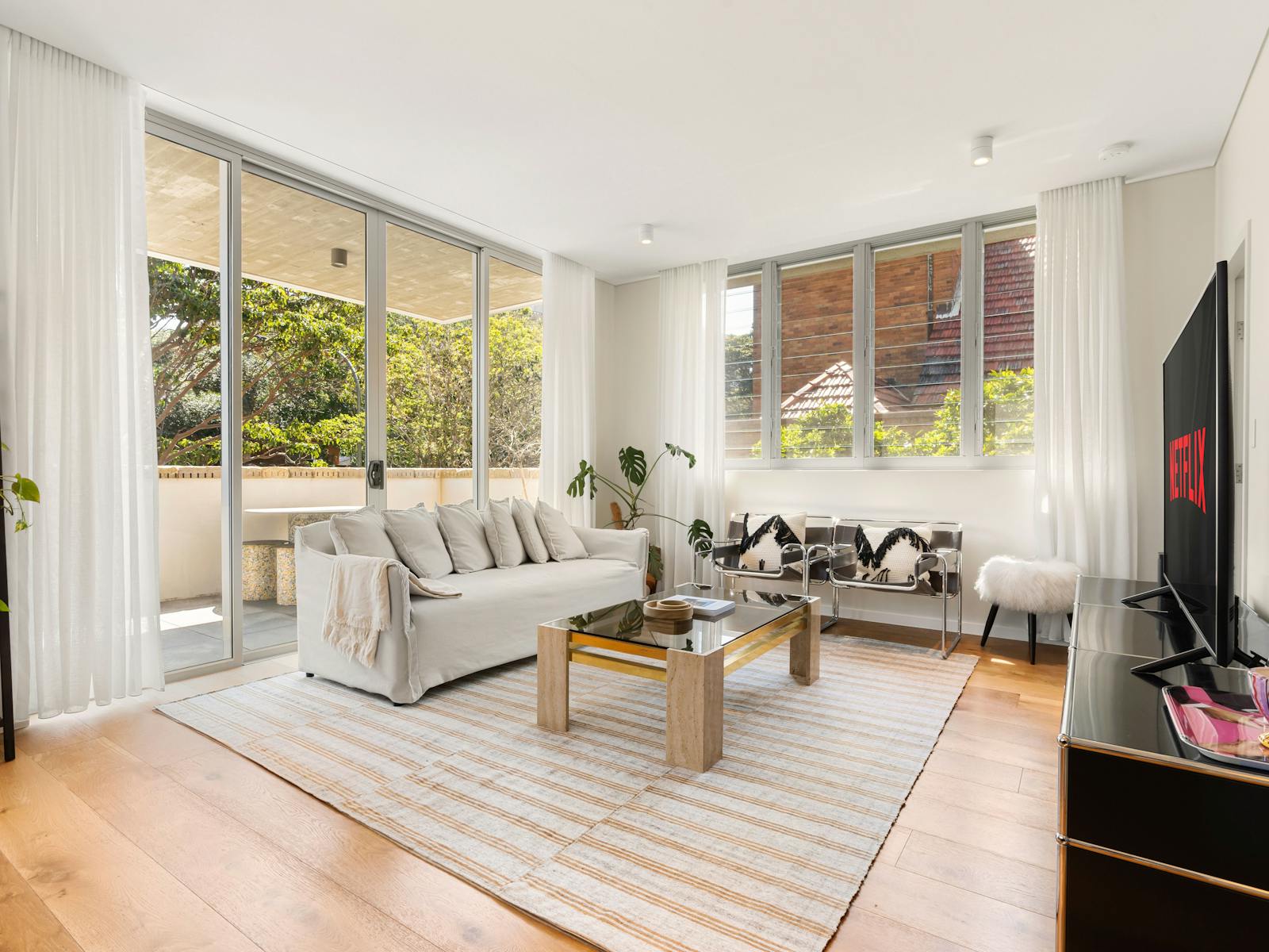 Living room with a Netflix screen, stylish furniture, and natural lighting.
