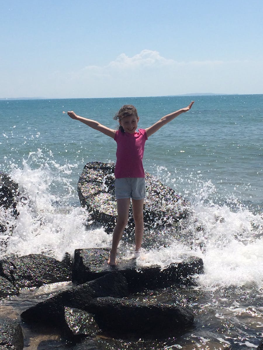 Girl on rocks with waves splashing in around her