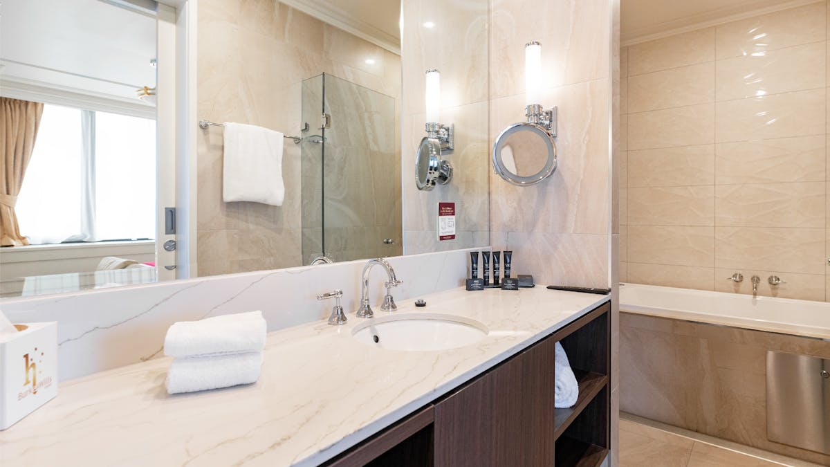 Luxury King Suite Bathroom featuring a large mirror, sink and bench overlooking a large jetted tub