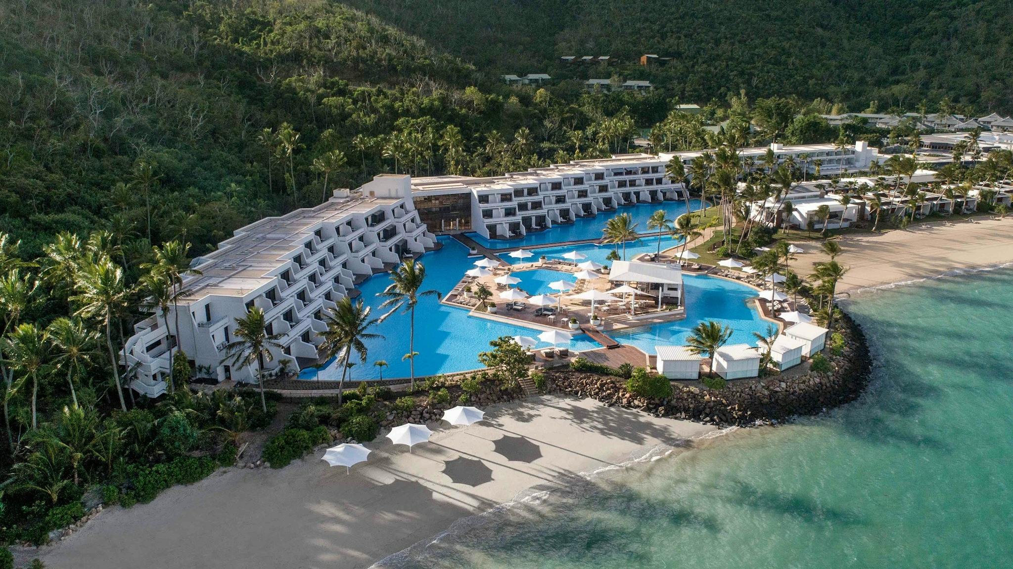 Aerial view of a luxurious resort along the beach with a large swimming pool in the front Aerial view of a luxurious resort along the beach with a large swimming pool in the front