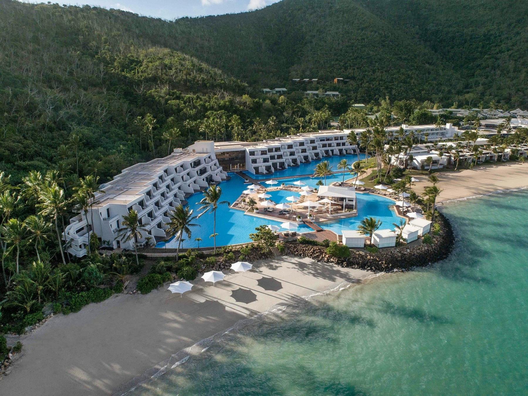 Aerial view of a luxurious resort along the beach with a large swimming pool in the front