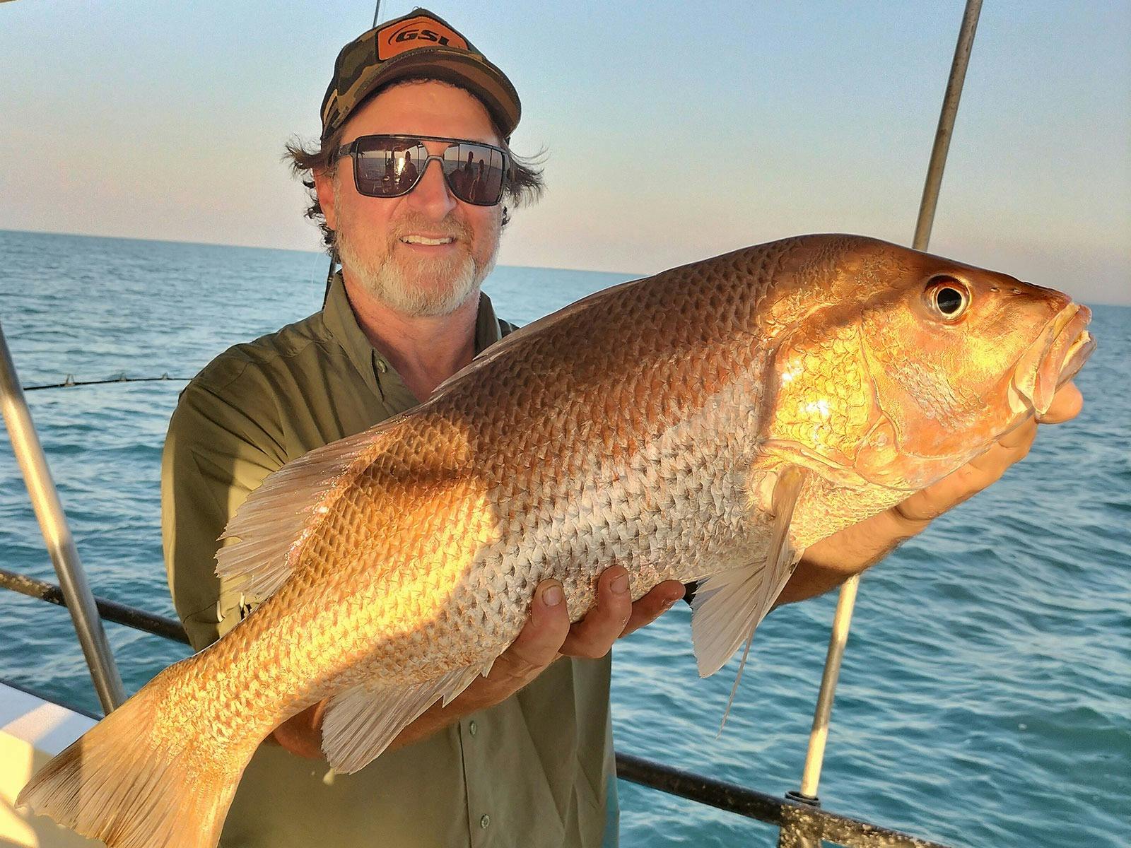 A man holding a fish on a Darwin Red Devil Charter.