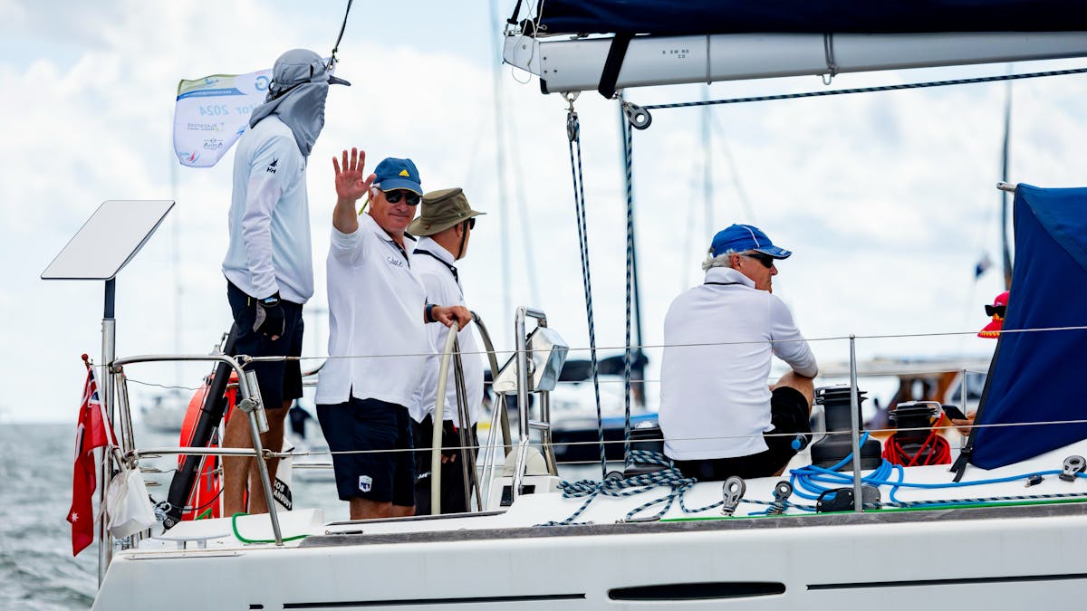 Four sailors with one waving at the camera from their yacht
