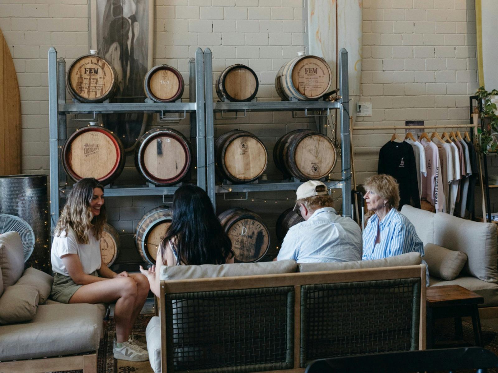 Couches and people in front of whisky and rum barrels at Hang 10 Distillery