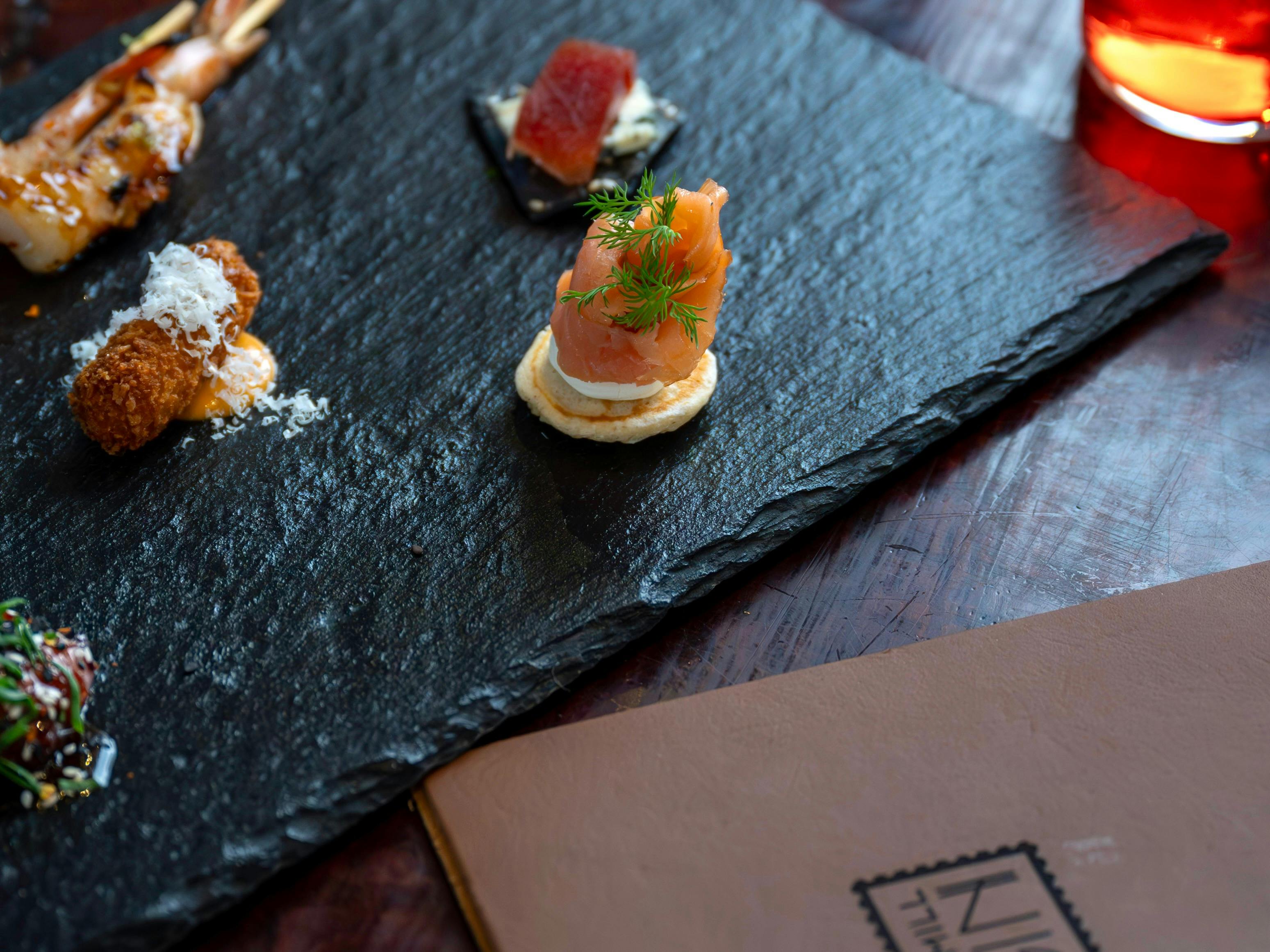 A slate platter with canapés of prawn, salmon, cheese and lavish