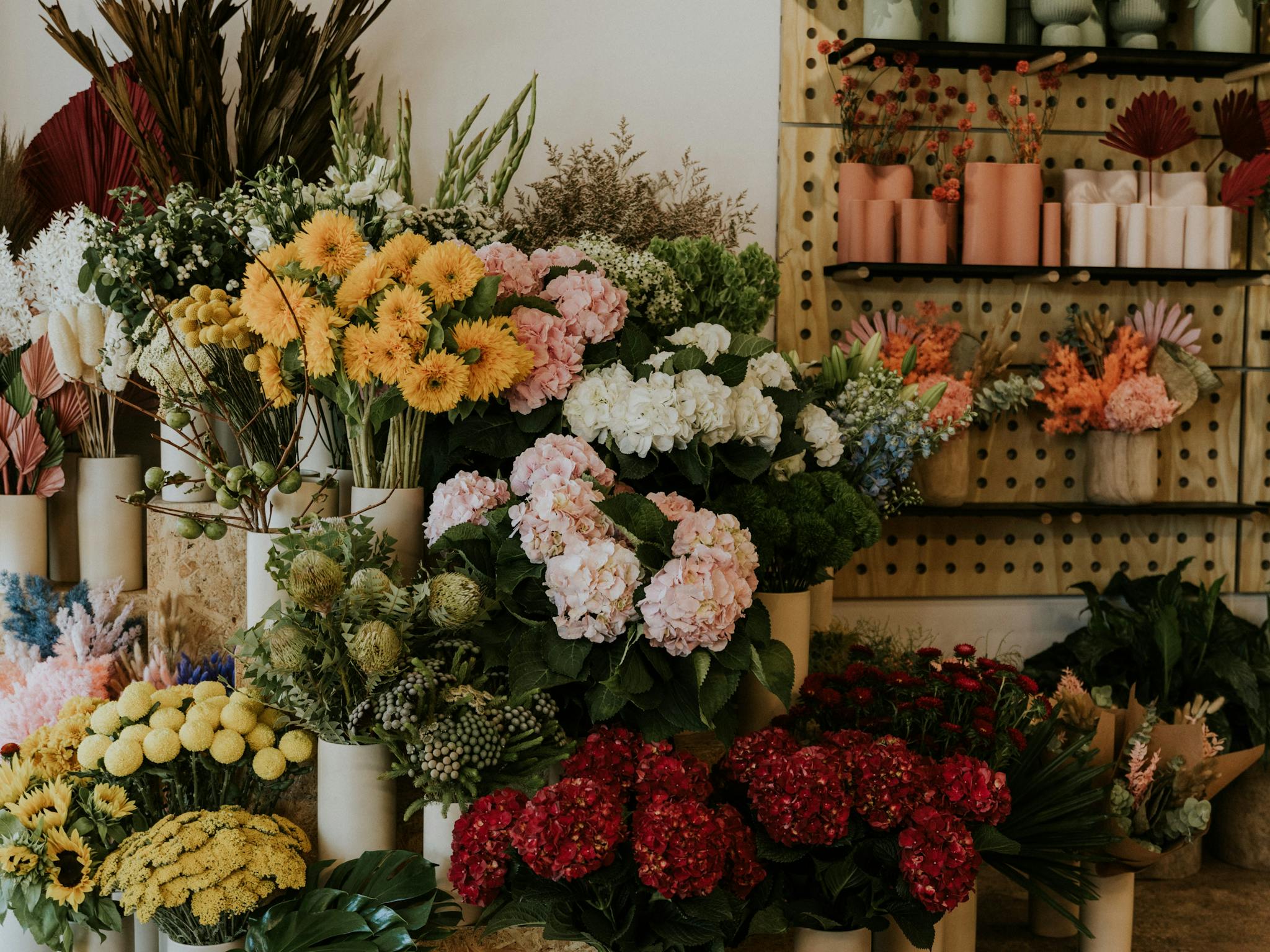 Fresh flower stand with colourful blooms and retail shelves with vases and dried arrangements