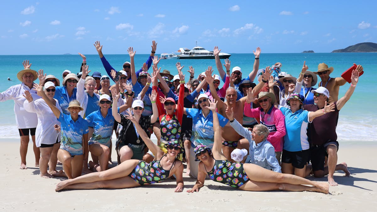 group photo on Whitehaven beach post swimming event with hands in the air celebrating
