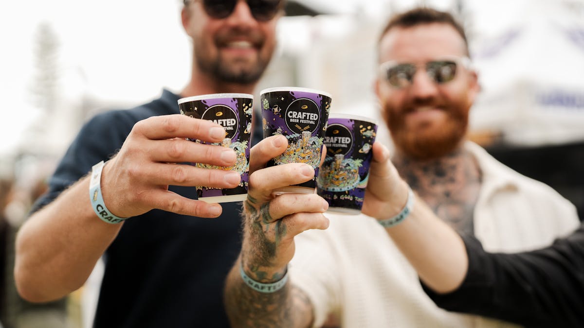 A small group of men cheersing beers at Crafted Festival