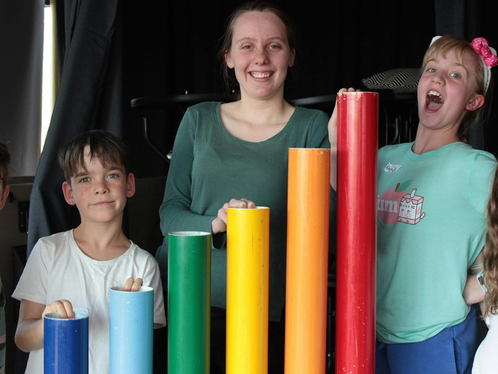 Three kids playing with rainbow percussion  tubes