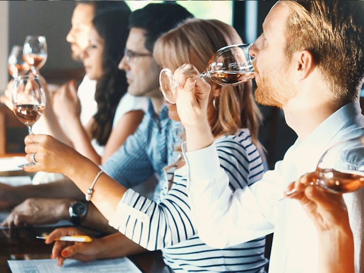 Group of people at a wine tasting sipping their glasses of wine