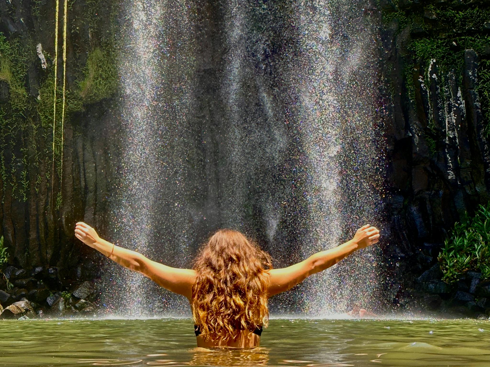 Woman standing in the water in front of Millaa Millaa Falls on the Atherton Tablelands Woman standing in the water in front of Millaa Millaa Falls on the Atherton Tablelands