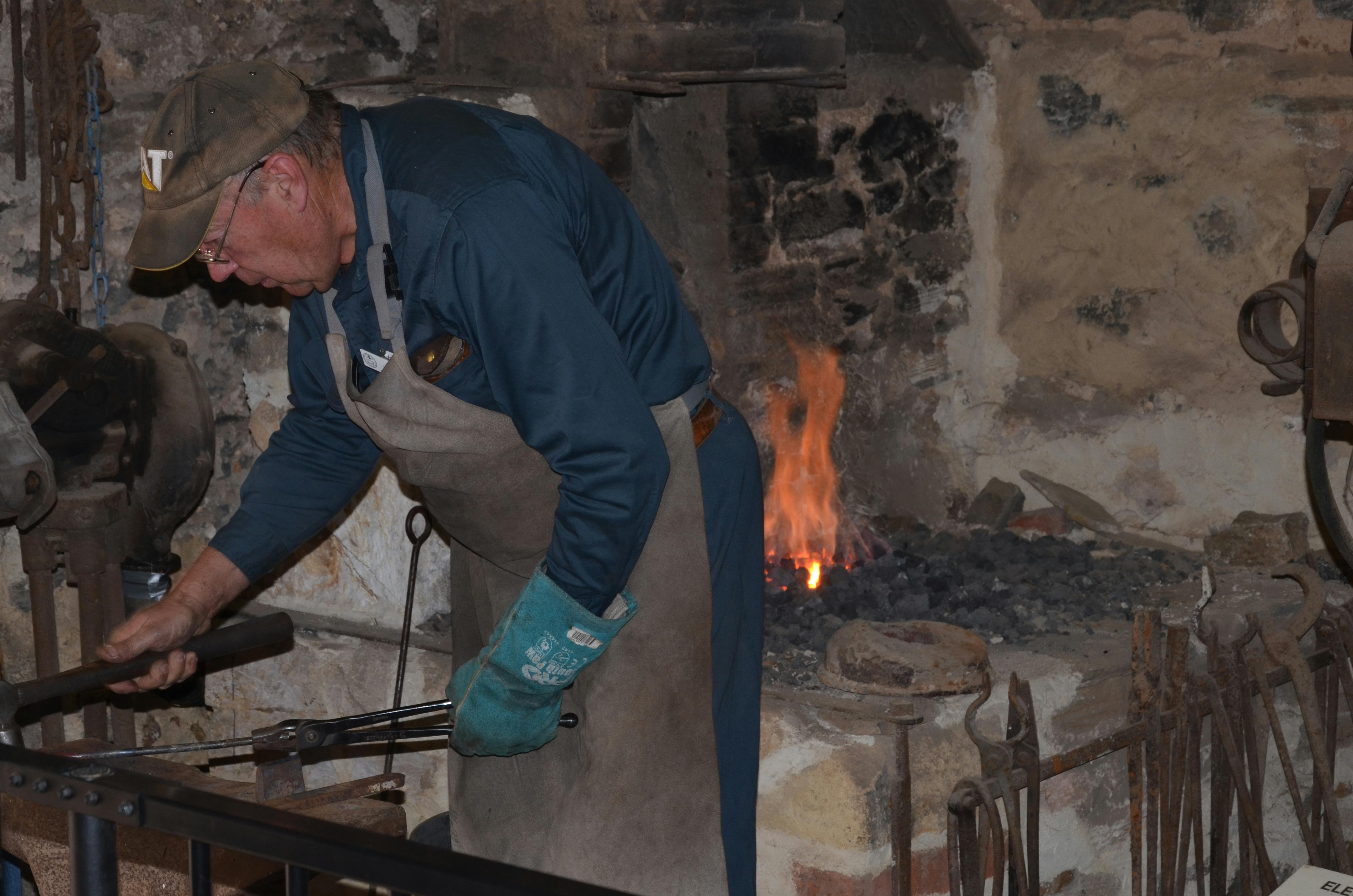 A blacksmith in action at one of the working forges.