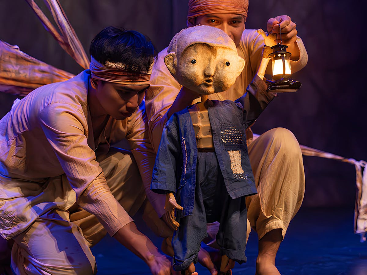 A puppet of a young boy holding a lantern.