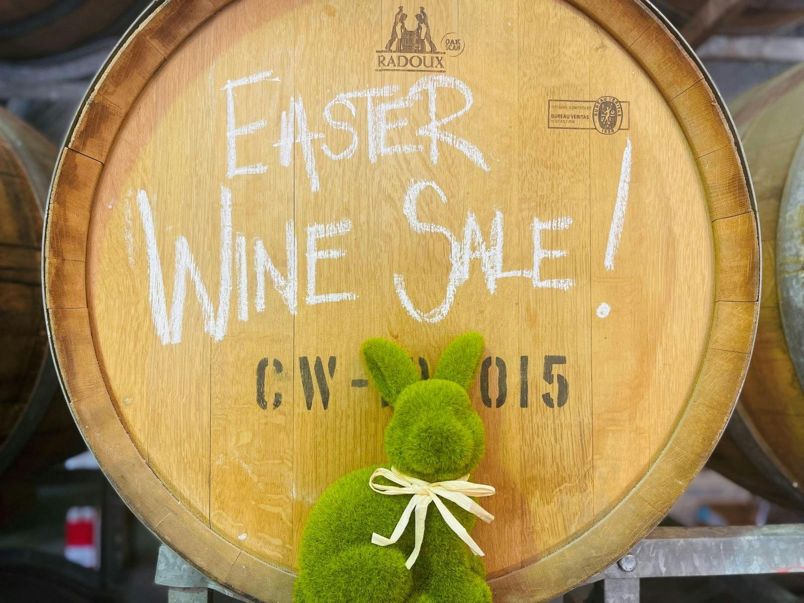 Wine barrel with easter wine sale writtnein chalk with a green bunny in foreground