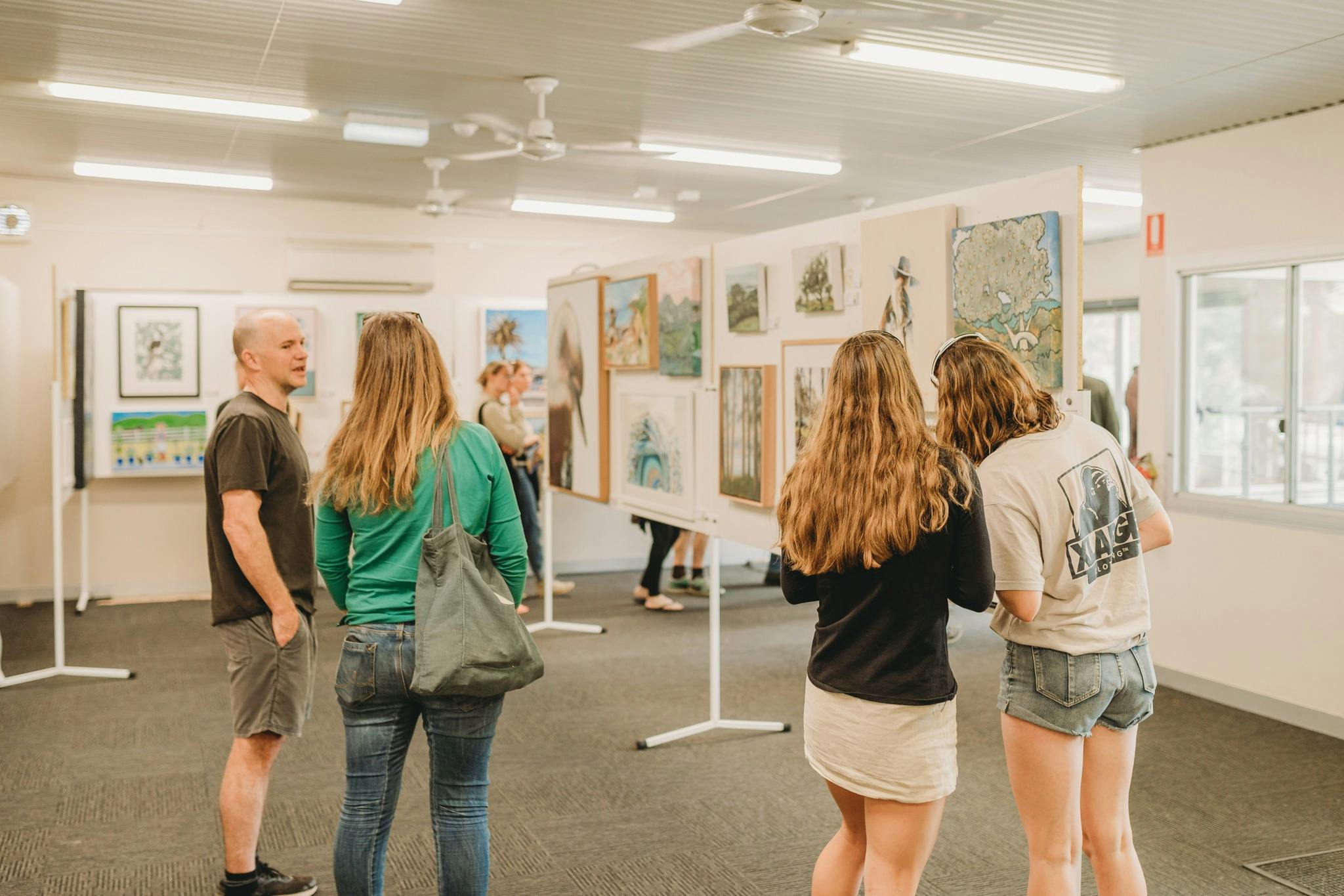 Two pairs of people looking at artworks on display
