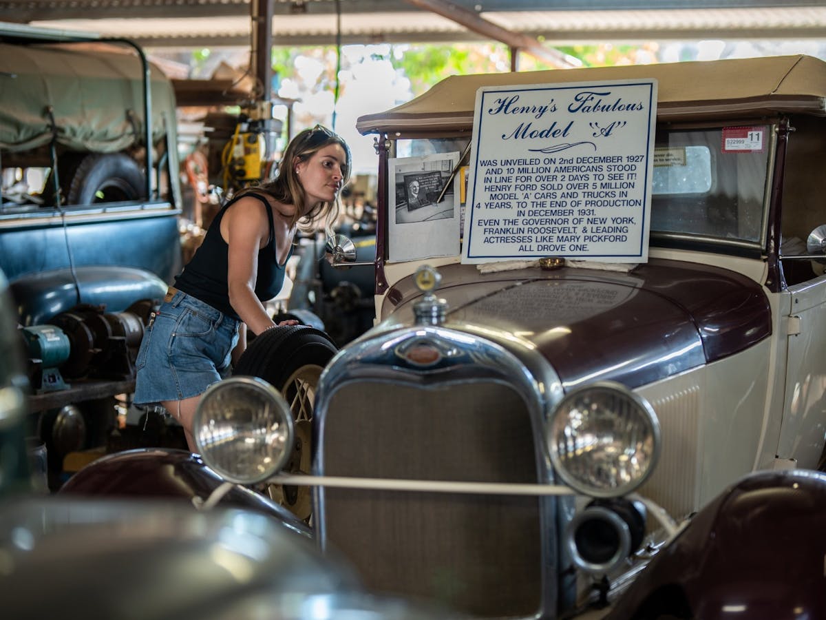 Woman peering into the window of a vintage car at the Tom Prior Ford Collection in Chillagoe.