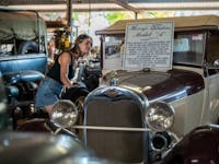 Woman peering into the window of a vintage car at the Tom Prior Ford Collection in Chillagoe.