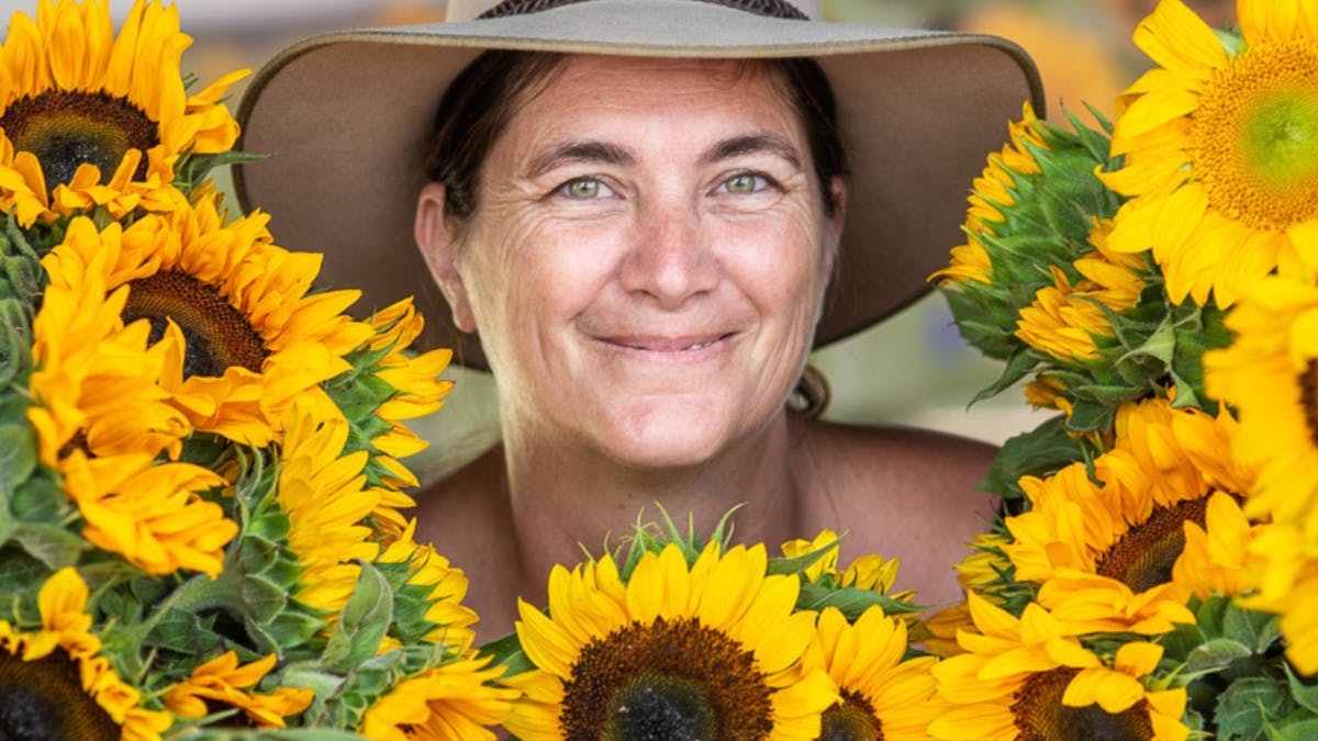 Smiling female farmer surrounded by sunflowers Smiling female farmer surrounded by sunflowers