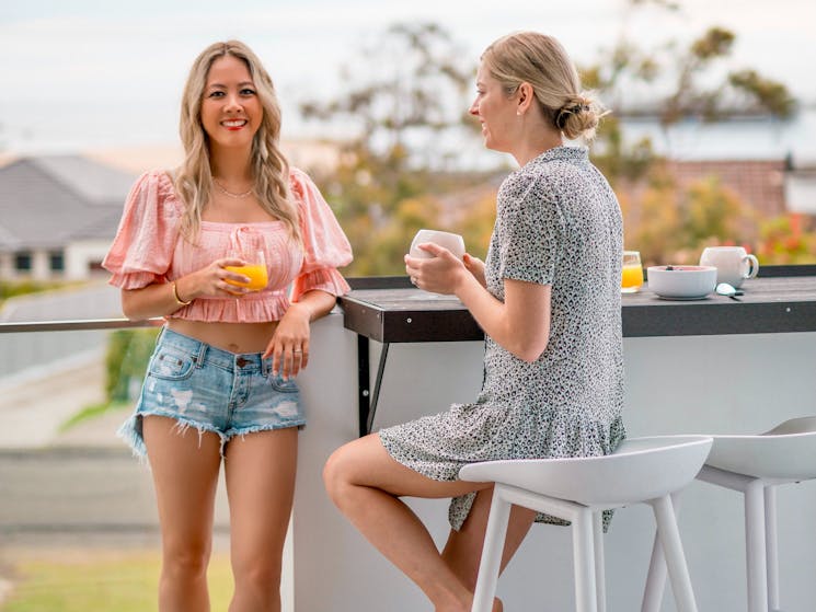 Two ladies having coffee at the breakfast bar on the balcony at Silvermere Coastal Retreat