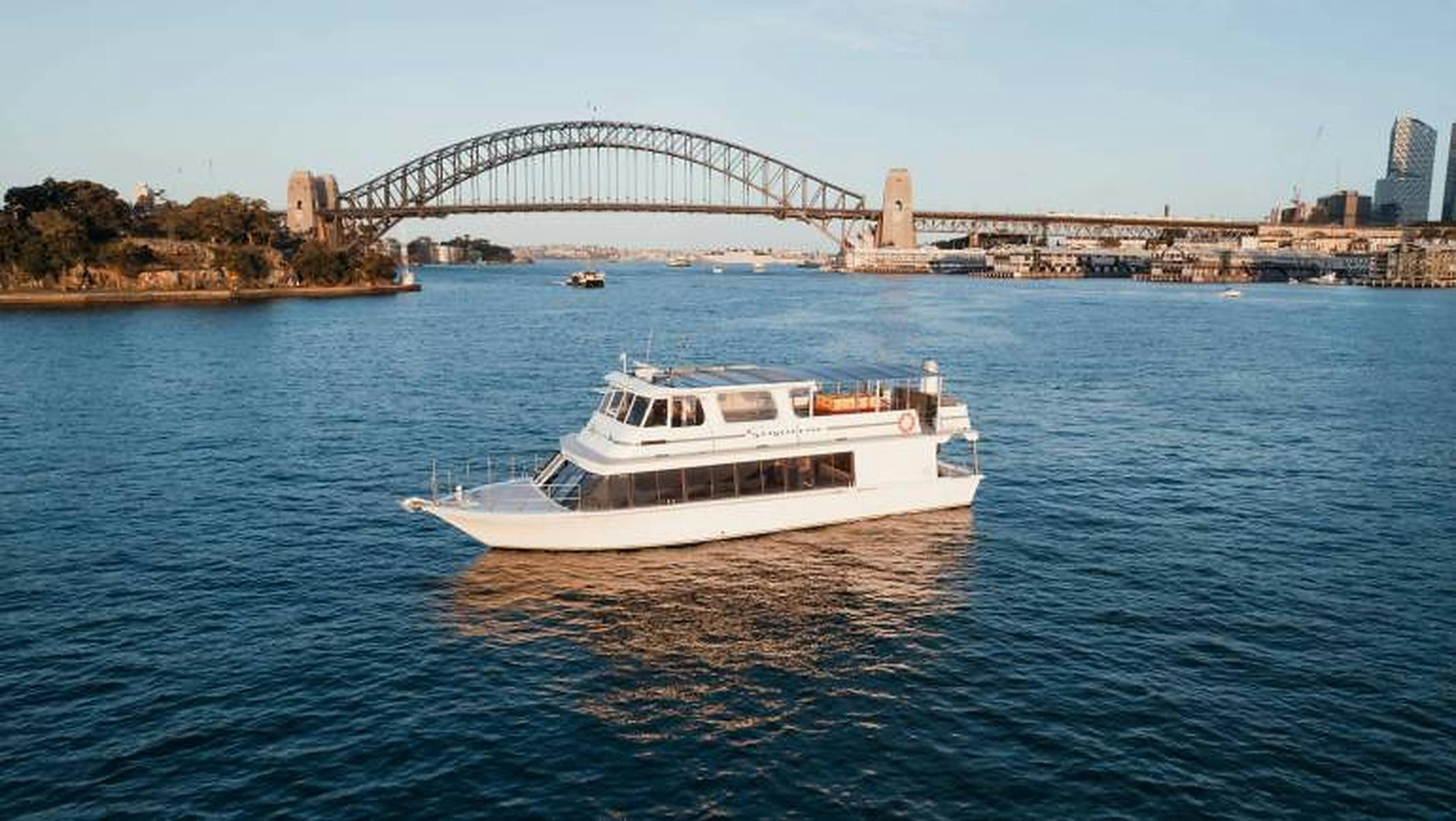 White motor cruiser Zahara on blue harbour water with the Sydney Harbour Bridge behind