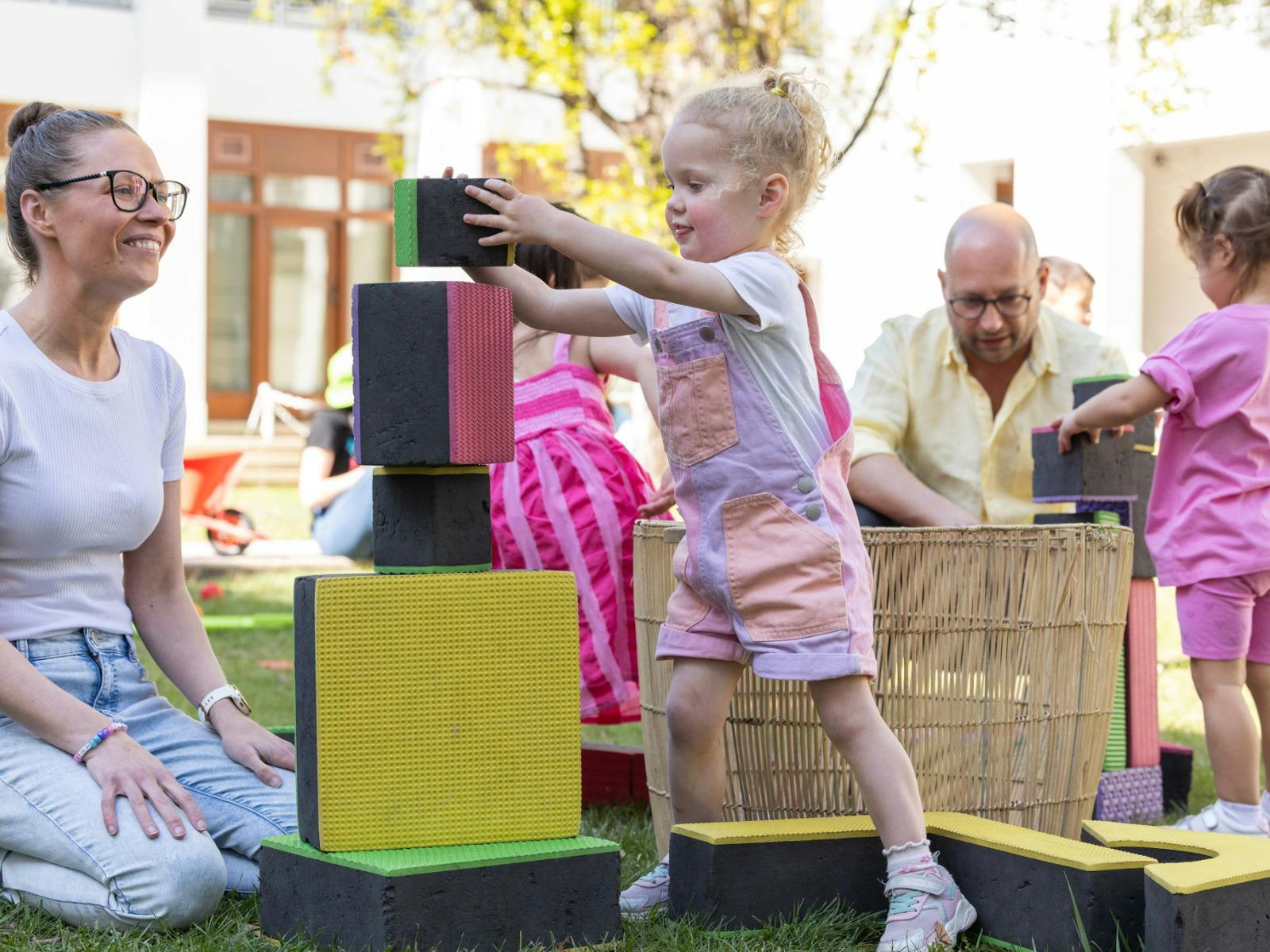 A young girl building a tower with large blocks.