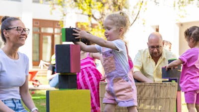 A young girl building a tower with large blocks.