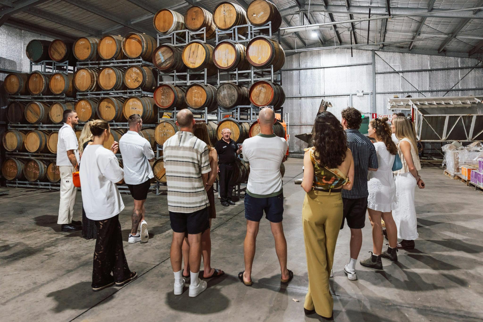 A group of people next to wine barrels at a local winery