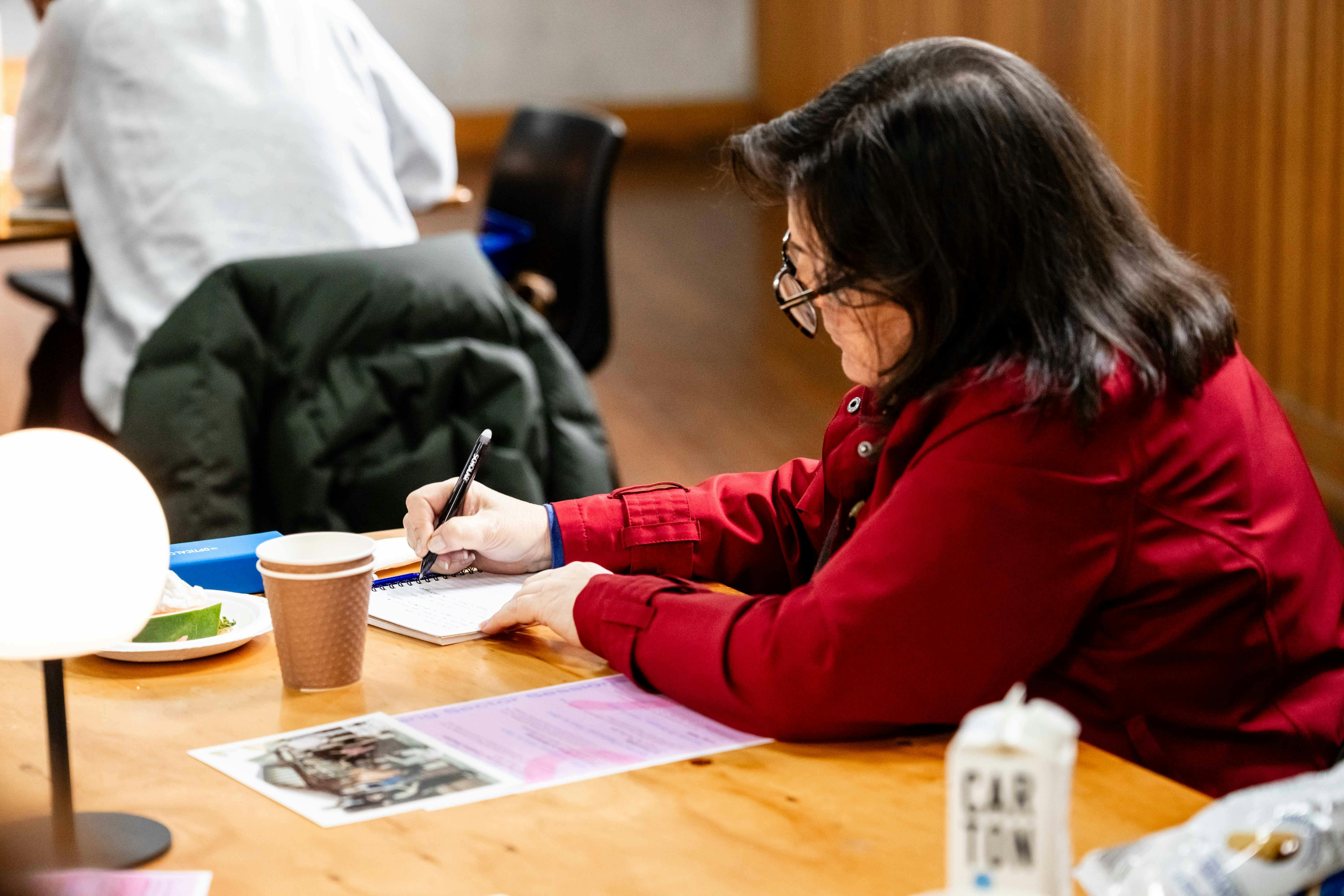 A photograph of a person sitting at a desk and writing.