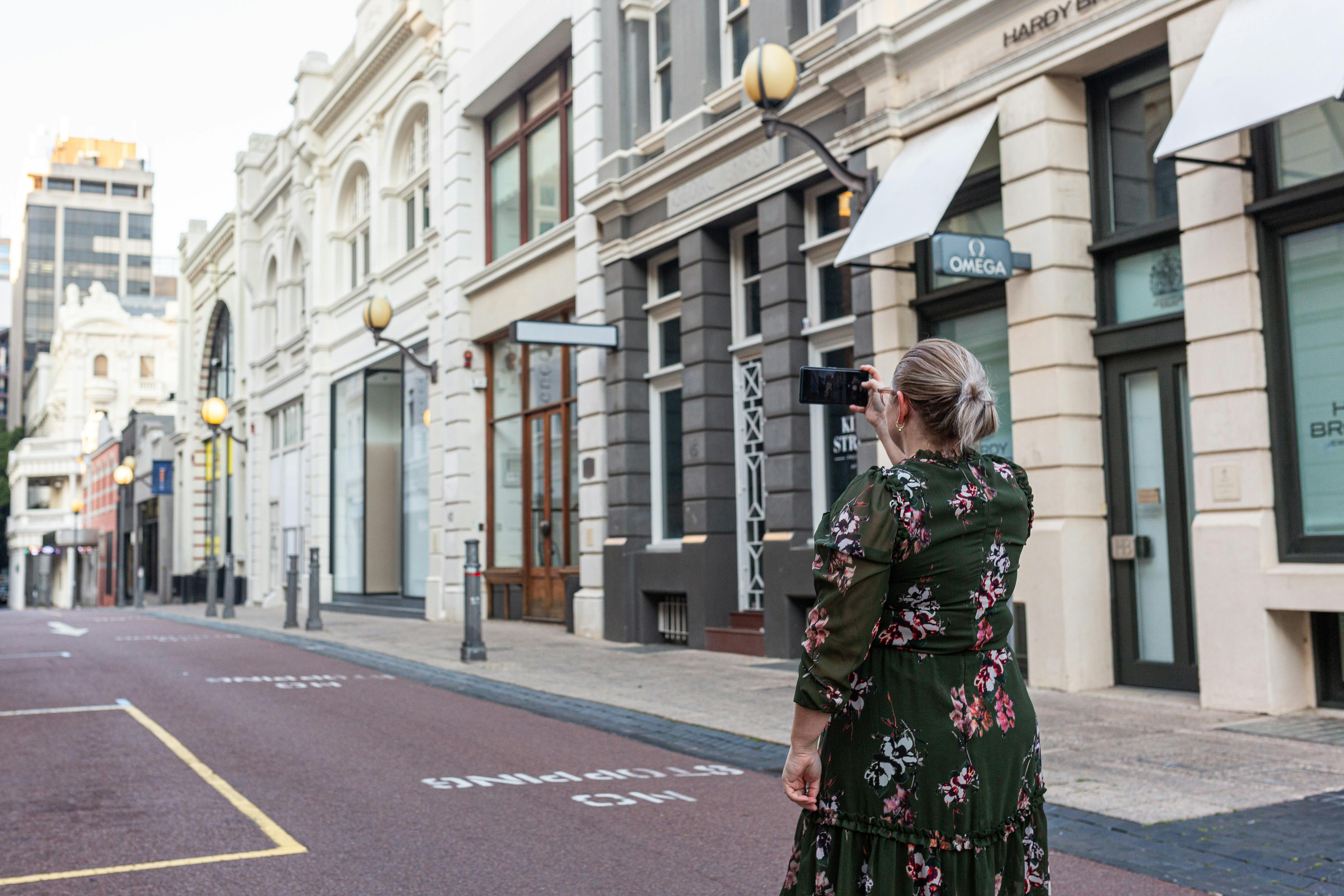 Woman in a dress taking a photo of historical Perth shopping district