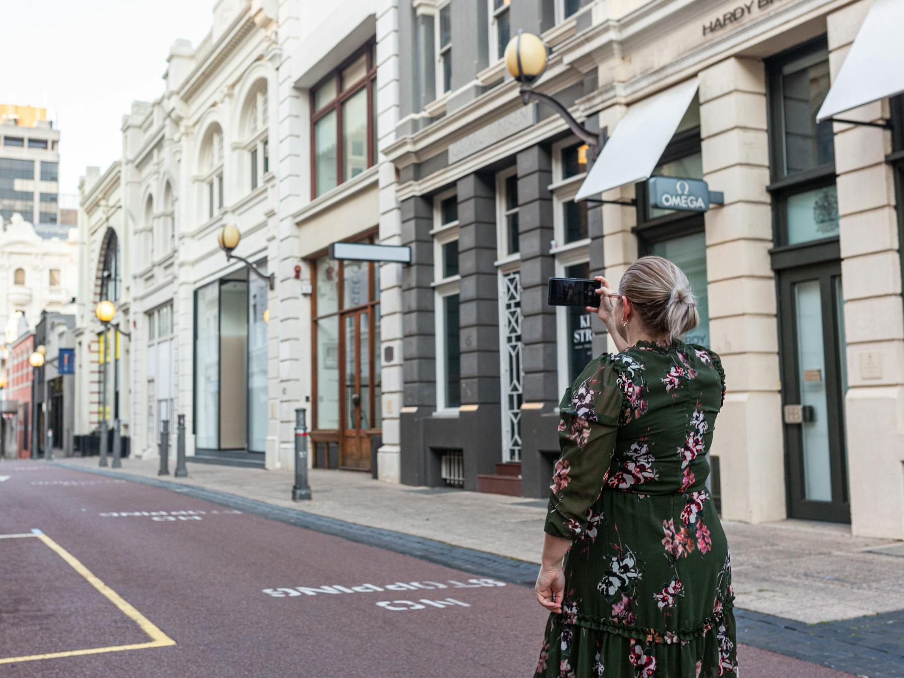 Woman in a dress taking a photo of historical Perth shopping district