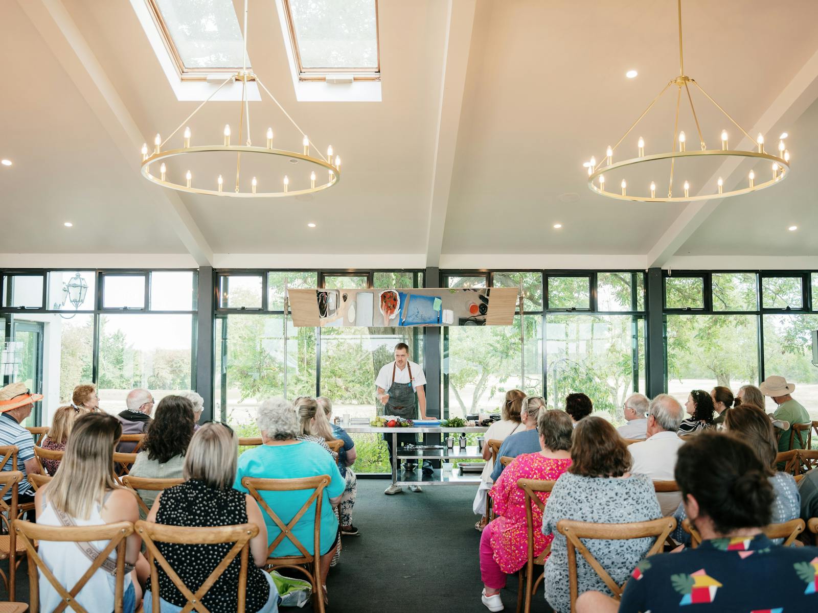 Chef standing under a mirror, large room with people seated theatre style