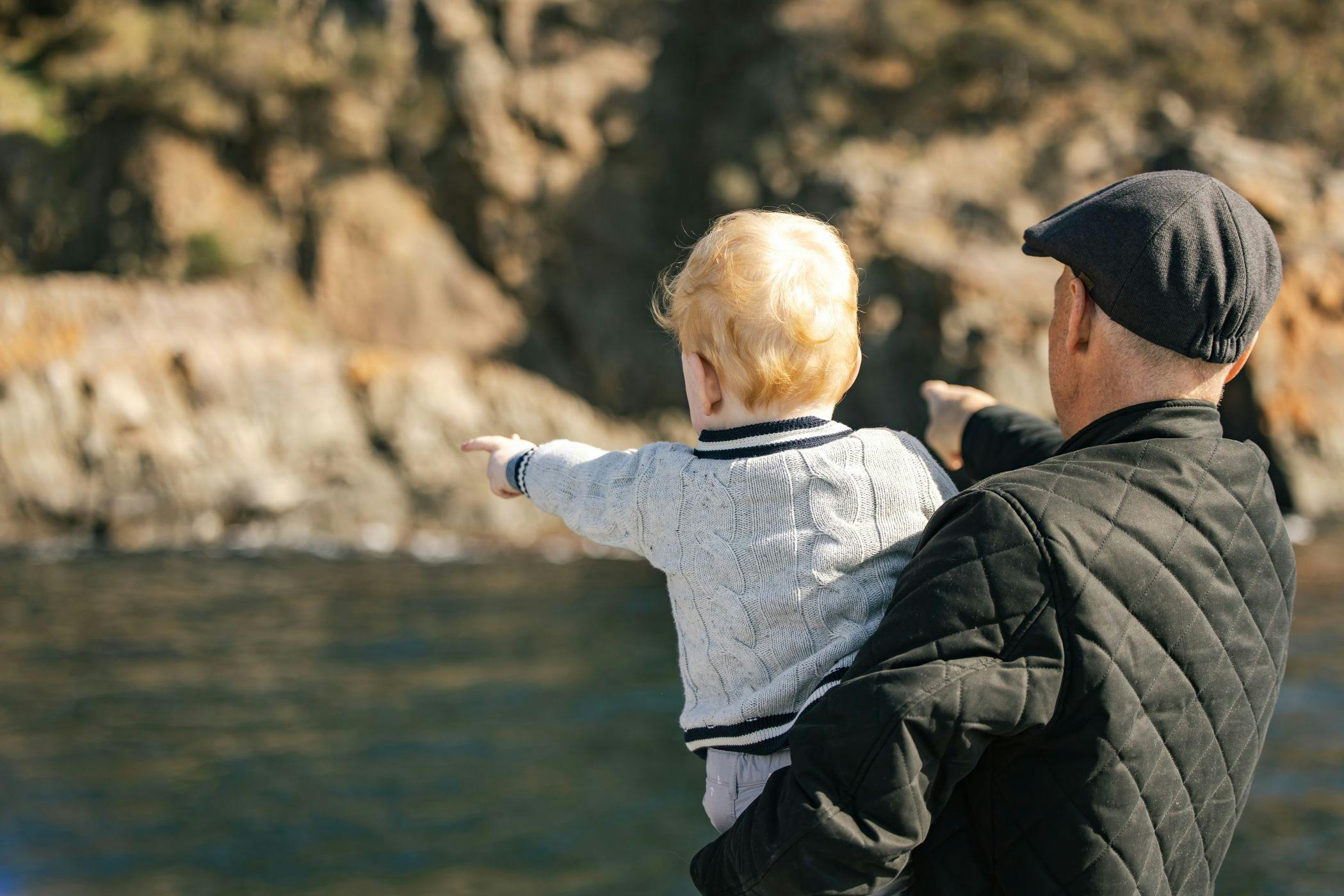A father holding his child point at the rock formations