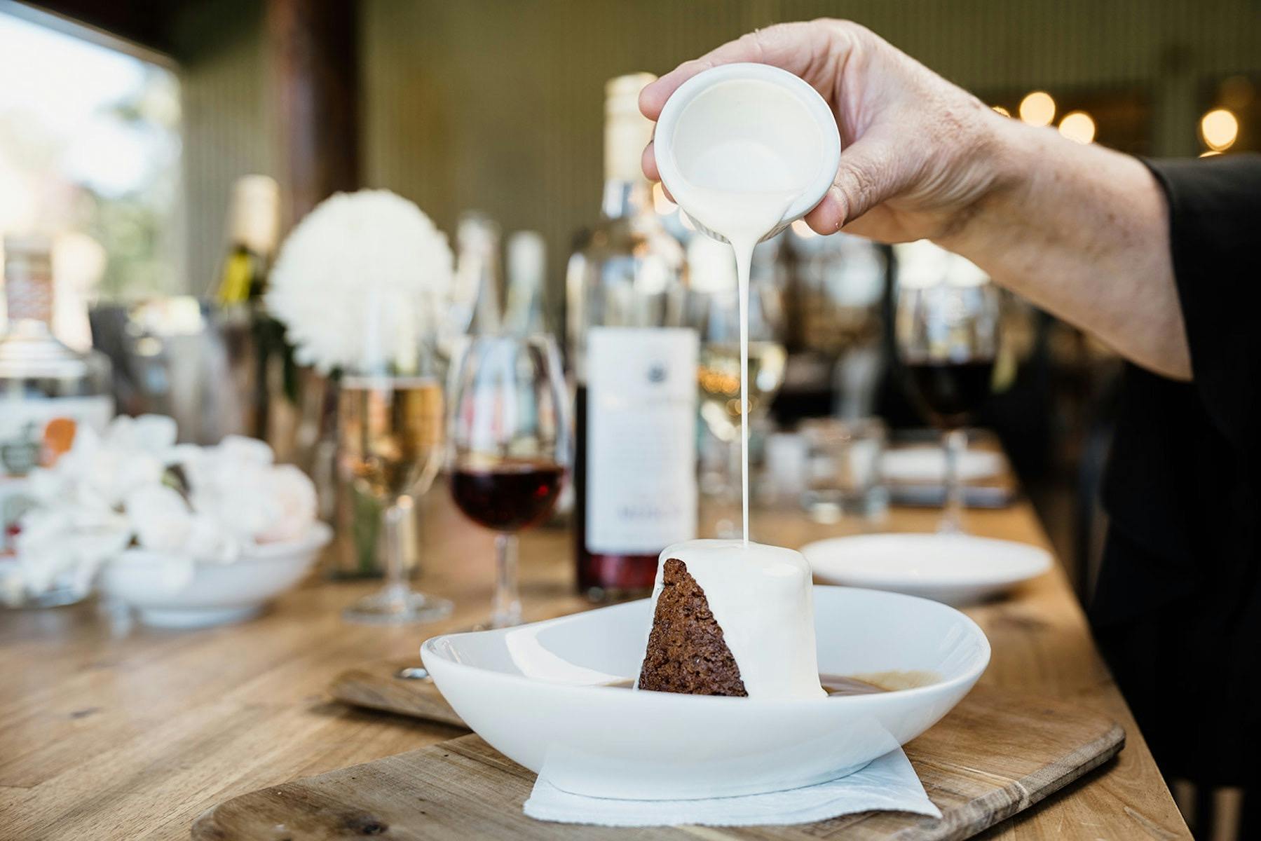 Pouring cream onto our signature dessert, sticky muscat pudding with muscat sauce.