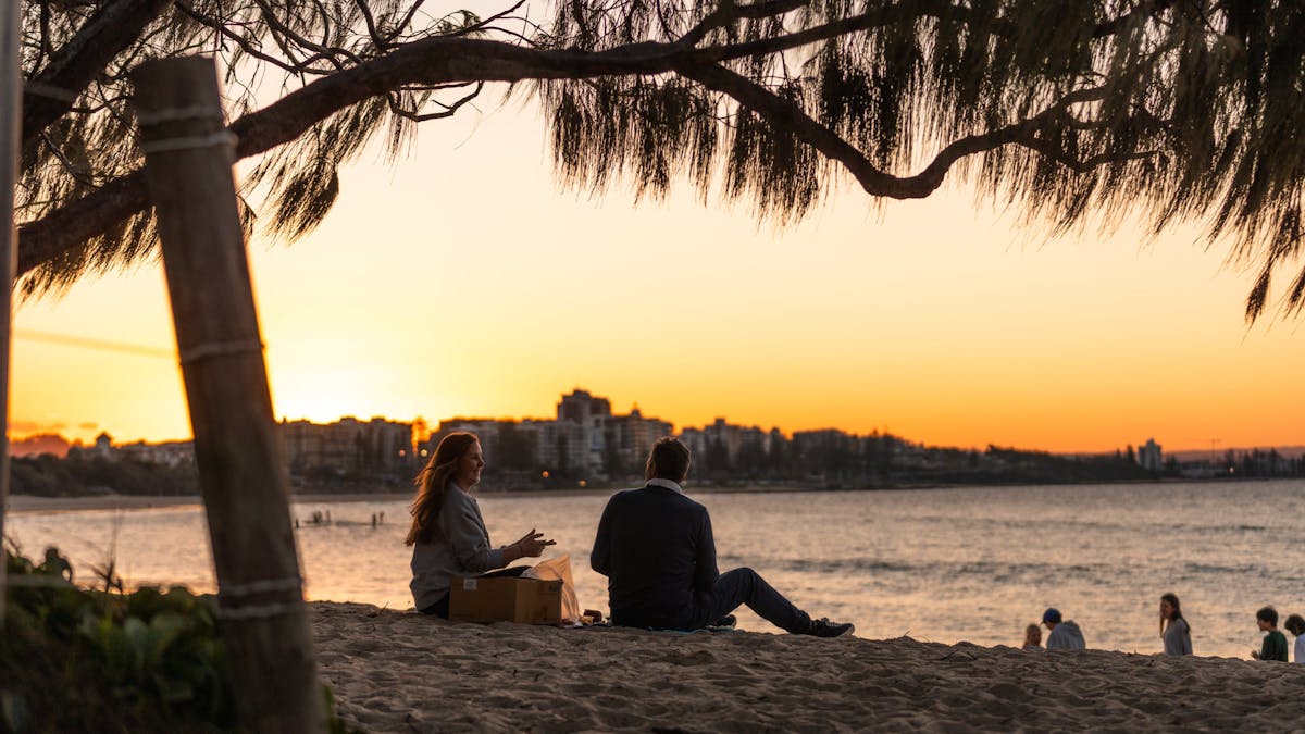 Shot of an older couple sitting on the beach watching the sunset