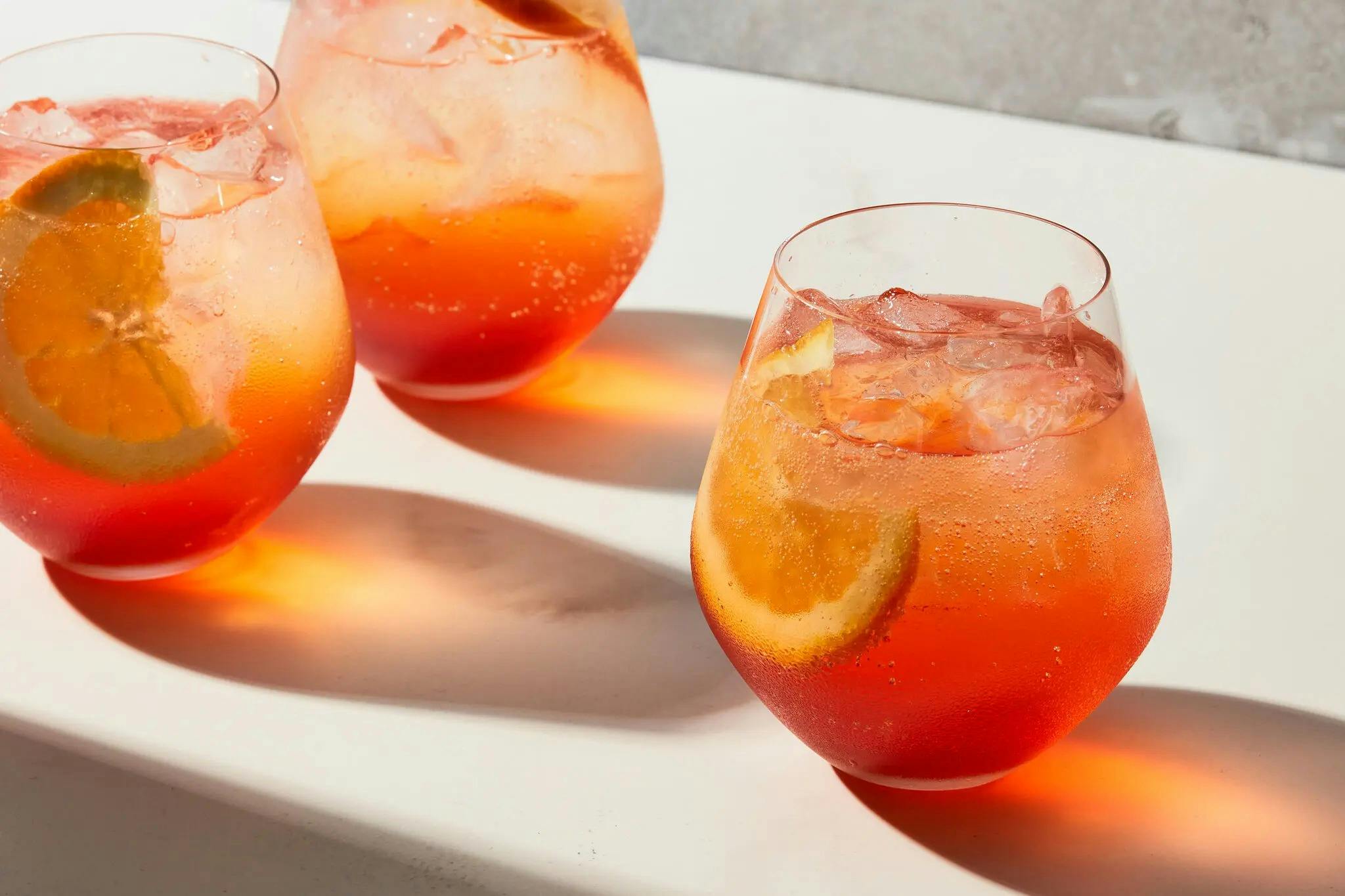 three glasses of aperol spritz on a white table