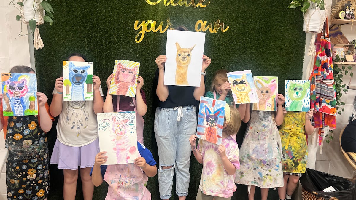 Childrens holding a pciture of a llama in our term drawing class