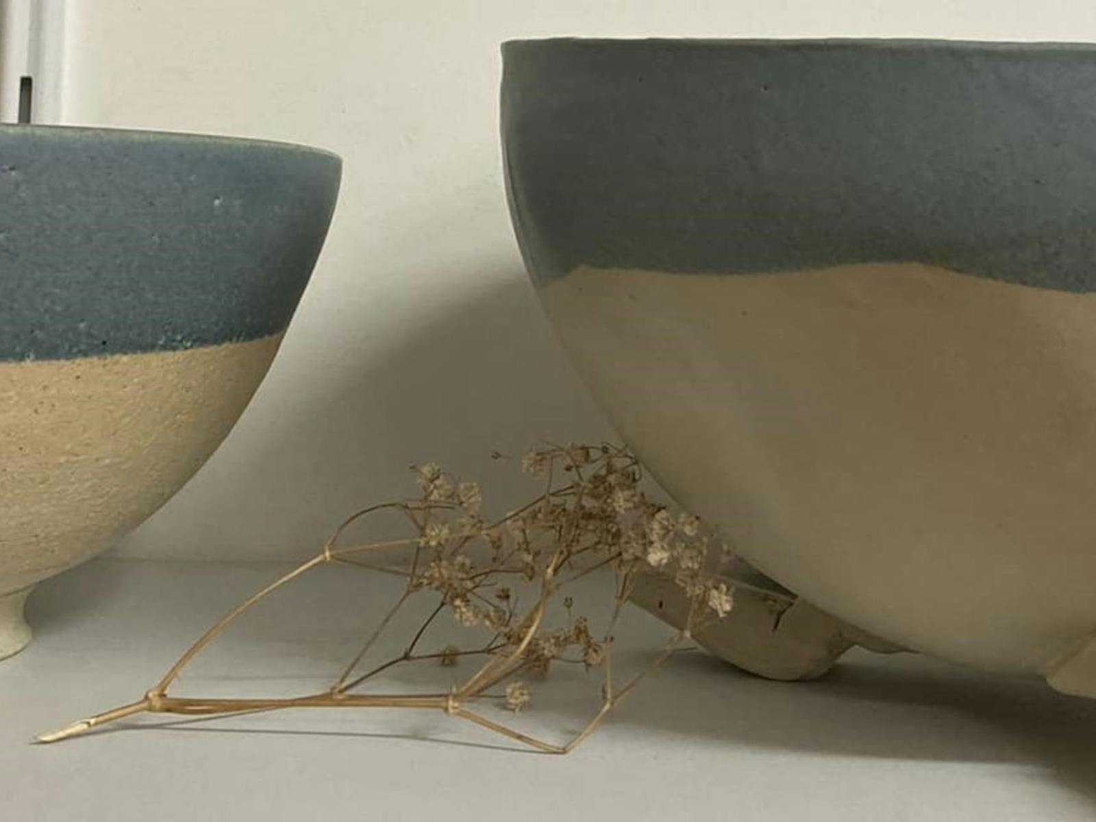 two beautiful blue and white ceramic bowls with a dried flower in between